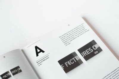 A graphic design book page features the text "F determining" in bold black letters on a white background. There is an icon of two A's and one C on the top right corner of the document. The overall aesthetic should be minimalist with clean lines and geometric shapes, reflecting a modernist style with a white paper background, minimalistic typography, and high resolution in the style of modernist designers. --ar 128:85