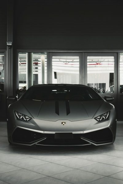 A Lamborghini huracan in the front of an empty car showroom, grey color scheme, unsplash photography style, minimalistic, dark background, high resolution --ar 85:128