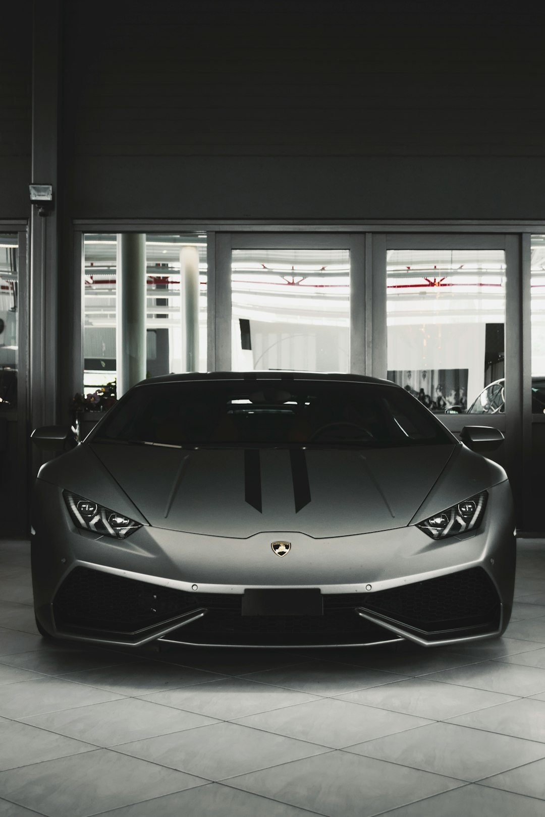 A Lamborghini huracan in the front of an empty car showroom, grey color scheme, unsplash photography style, minimalistic, dark background, high resolution –ar 85:128