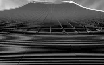 The top of the Maitama Tower in black and white, with its iconic patterned facade, features rows of vertical lines that create an elegant texture. The sky is clear above it, adding to the overall minimalist aesthetic of the building. Shot from below using a Canon EF macro lens at f/2 for sharp detail capture in the style of minimalism. --ar 128:79