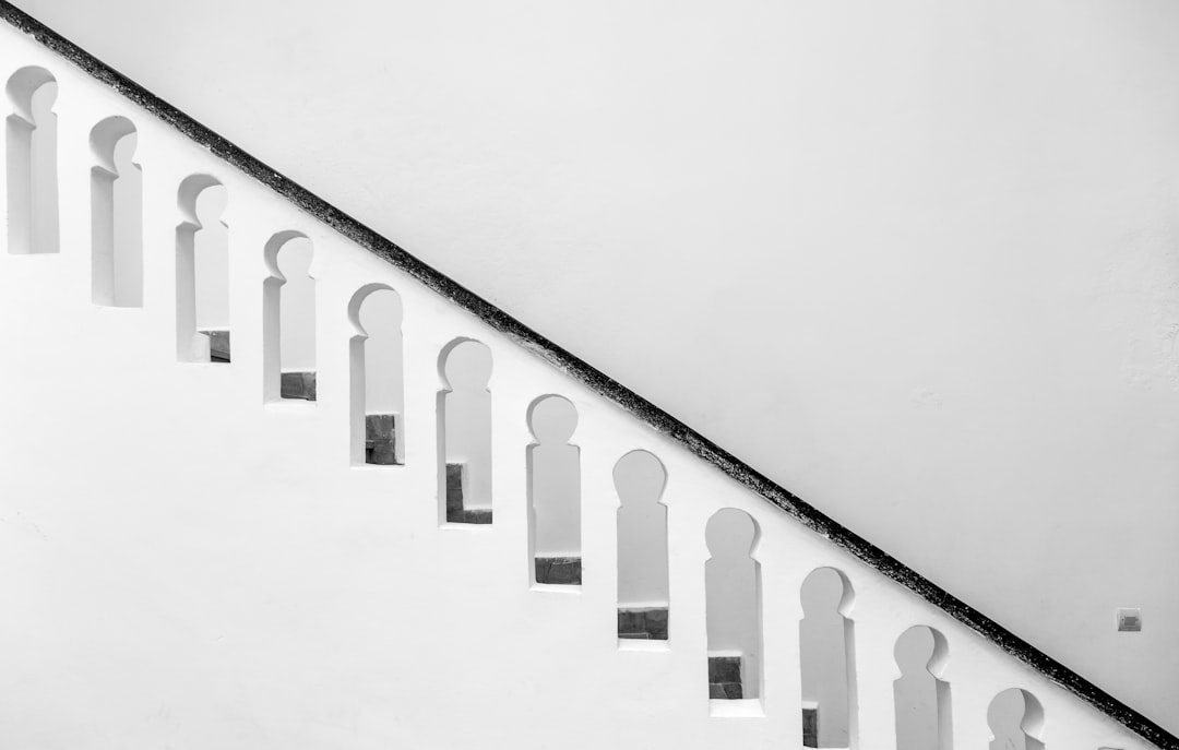 Stairs with white arches, black and white photography with a white background, simple composition focusing on architectural details and geometric shapes with a minimalist and symmetrical layout. –ar 128:81