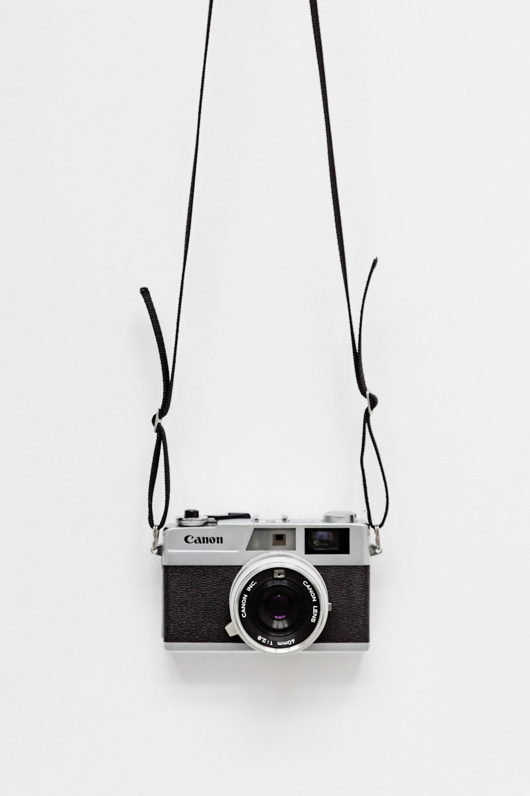 A silver ” humorous” camera hanging on the wall, white background, simple style, minimalist style, high definition photography –ar 85:128