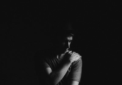 Black and white photography of a man in a dark room with a sad face, hand on his chin in the style of [Ansel Adams](https://goo.gl/search?artist%20Ansel%20Adams). --ar 128:89