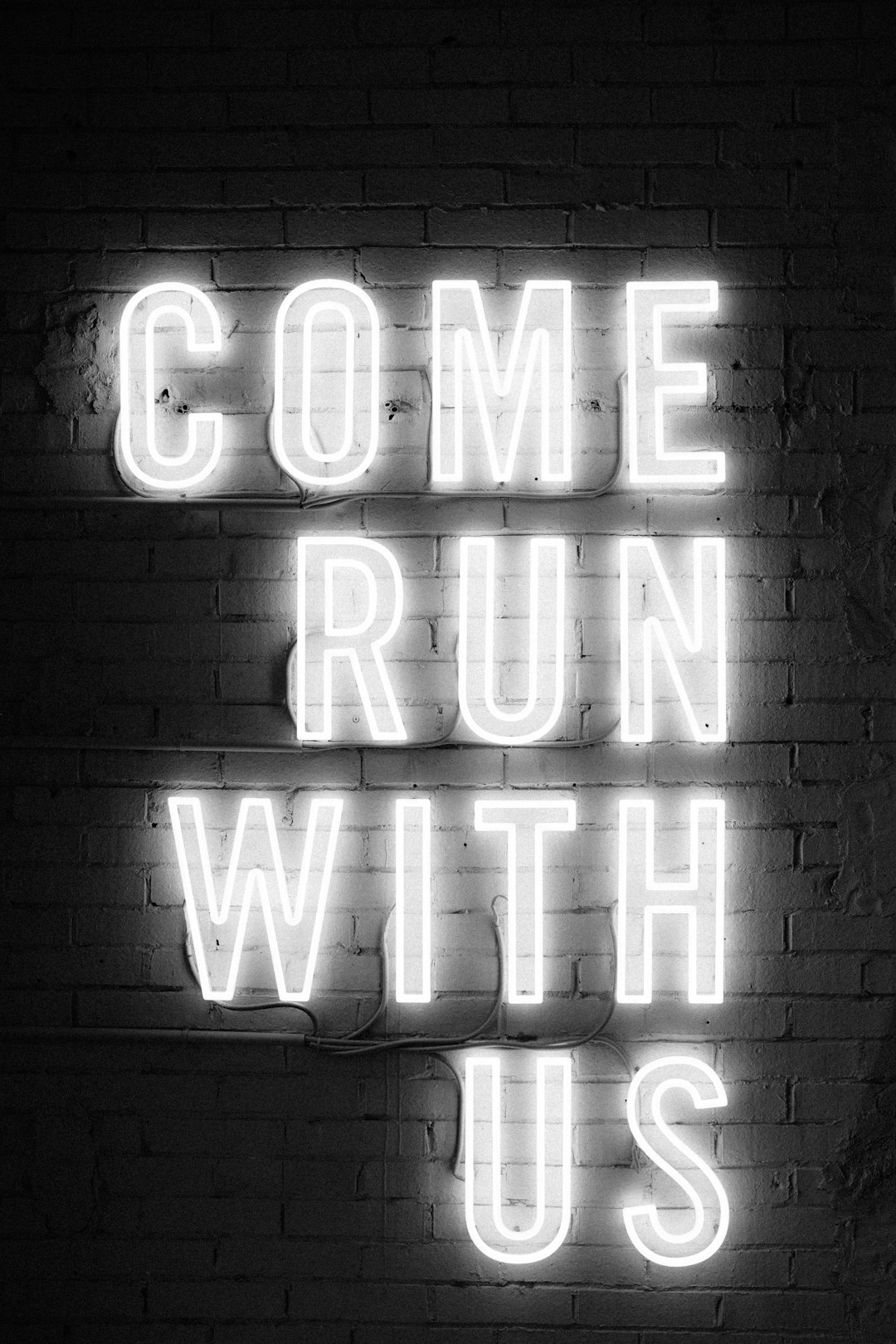 white neon sign with the text ” acres come run WITH US” on white brick wall, black and white photography, minimalism, –ar 85:128