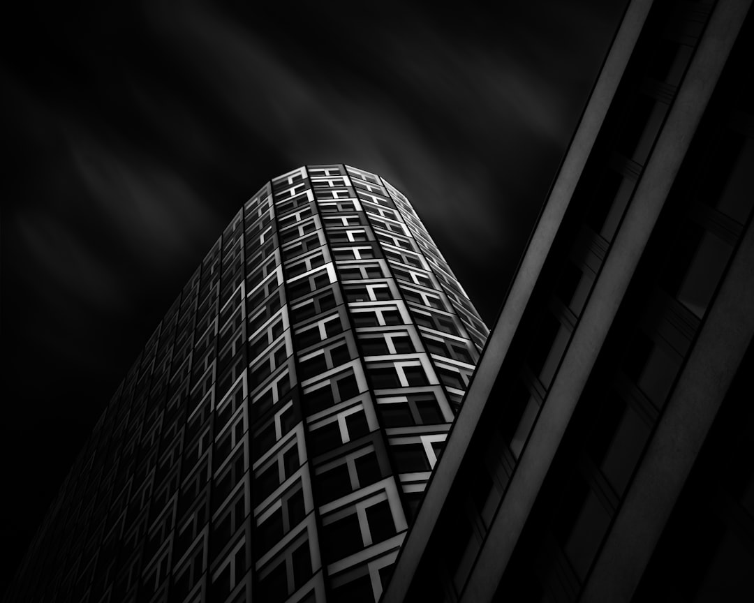 black and white photography, skyscraper with geometric pattern, dark sky, dramatic lighting, sharp focus on building texture, high contrast, urban architecture –ar 64:51