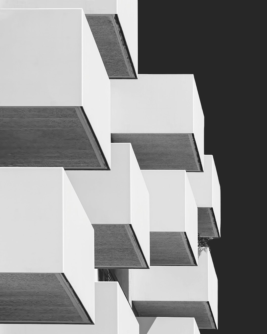 A black and white photograph of an abstract geometric design featuring balconies on the building, showcasing architectural elements in sharp focus against a monochromatic background. The composition emphasizes clean lines and minimalism, creating a visually striking image that evokes modernity with its simplicity and elegance. This piece is designed to convey artificial intelligence-inspired aesthetics through its symmetrical layout and harmonious color palette in the style of minimalism. –ar 51:64