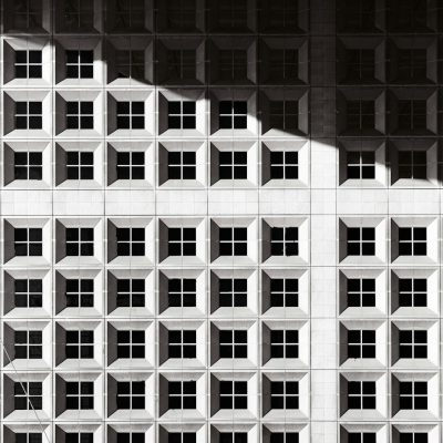 black and white geometric grid building facade, shadows cast on wall, architectural photography --ar 127:128