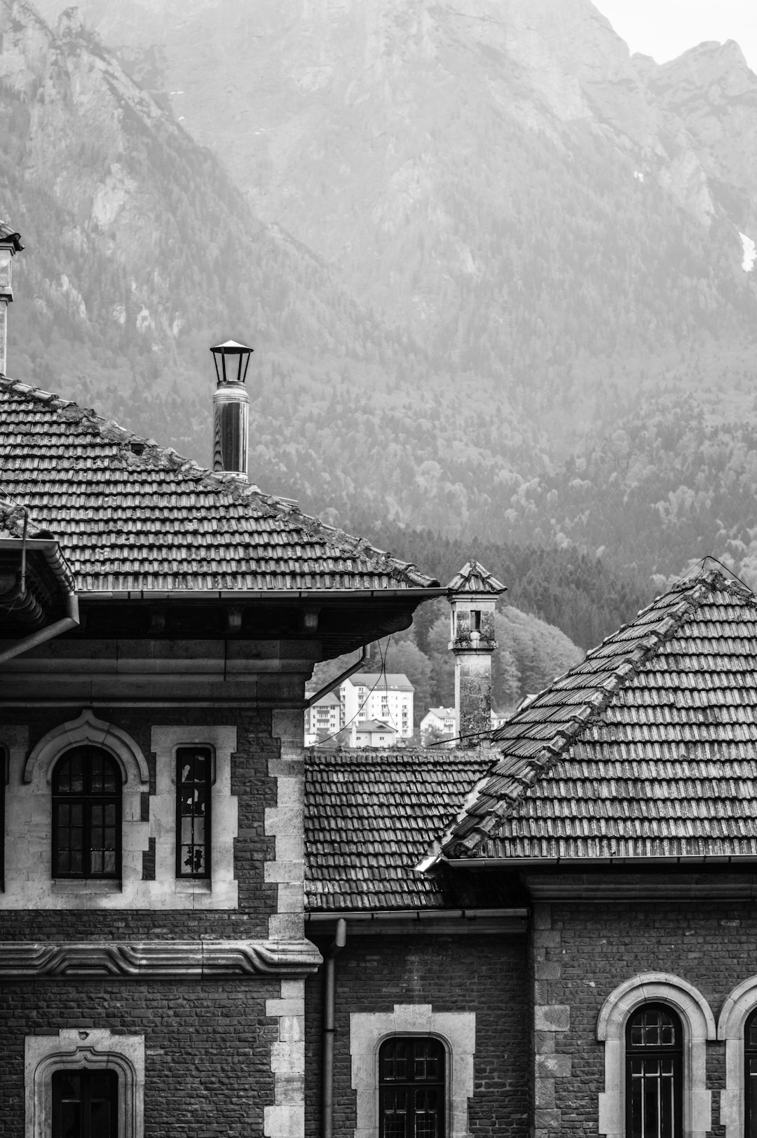 black and white photography of old architecture in the alps, mountains behind the buildings, roof tiles, architecture details, architecture photography, old town, mountains in background, –ar 85:128