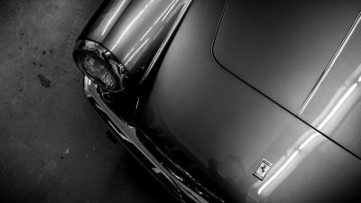 Close up of the front fender and headlights on an old grey sports car, black and white film photography, in the style of Hasselblad photography, soft shadows, no contrast, clean sharp focus, minimalistic, in the style of advertising photography. --ar 16:9