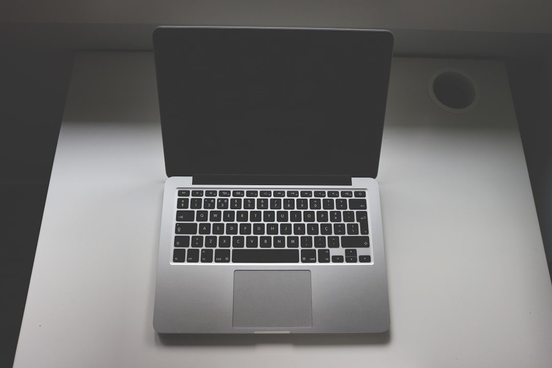 A Macbook Pro laptop on a white table, top view, in a dark room, minimalist, product photography, high resolution. –ar 128:85