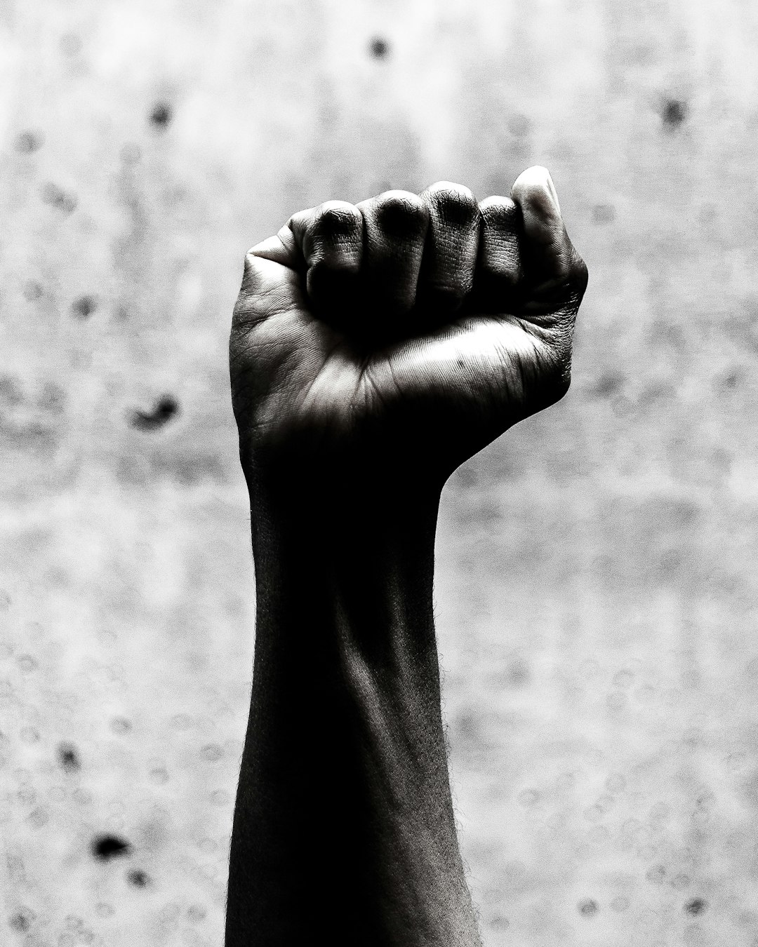 Black and white photography of one arm raised with fist up, black power concept –ar 51:64