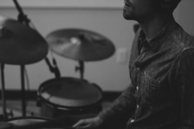 A black and white close up photo of an African American man playing the drums in his home studio, in the style of unsplash photography. --ar 128:85