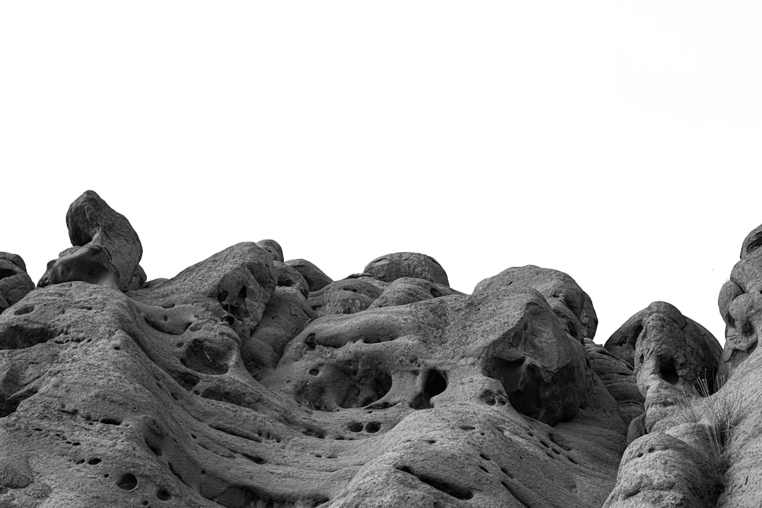 white background, a black and white photograph of rock formations that resemble giant heads in the desert –ar 128:85