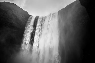 black and white photo of the waterfall in Iceland, low angle shot, grainy filmic feel, very high contrast, blurred edges, atmospheric, foggy, dark, dramatic, monochrome, soft lighting, cinematic. --ar 128:85