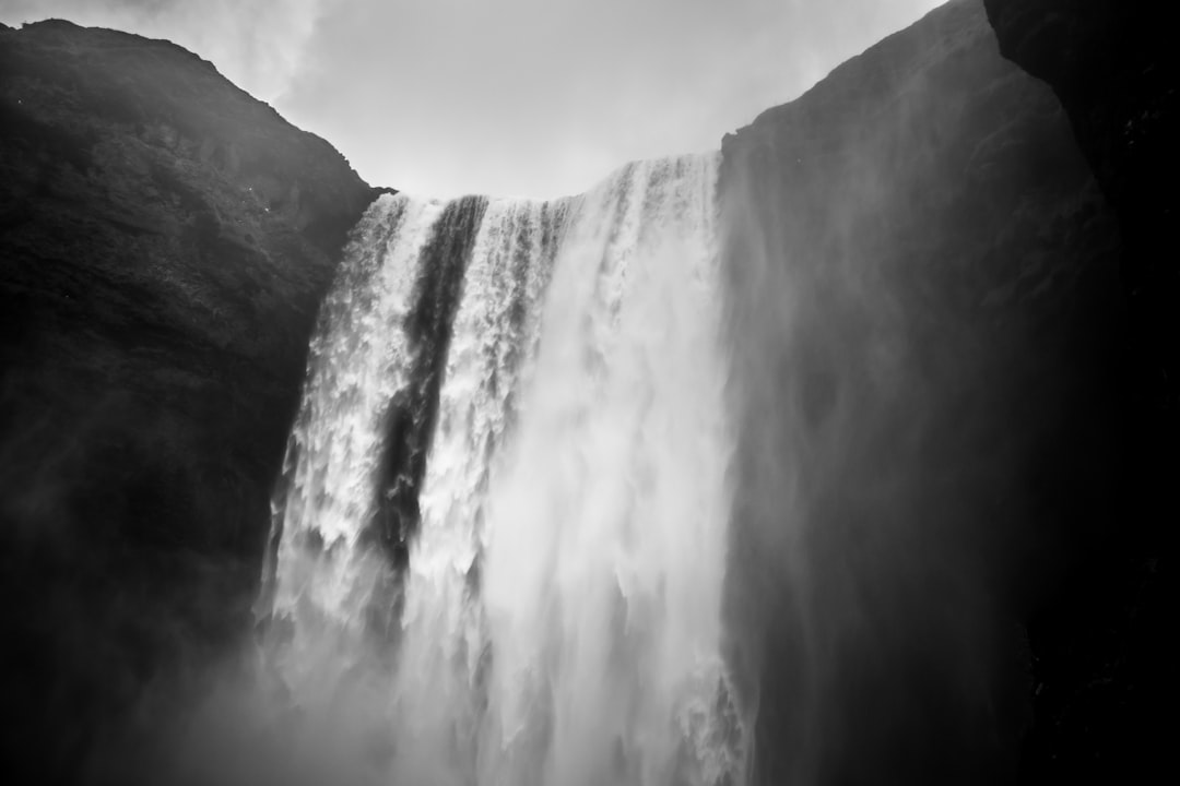 black and white photo of the waterfall in Iceland, low angle shot, grainy filmic feel, very high contrast, blurred edges, atmospheric, foggy, dark, dramatic, monochrome, soft lighting, cinematic. –ar 128:85