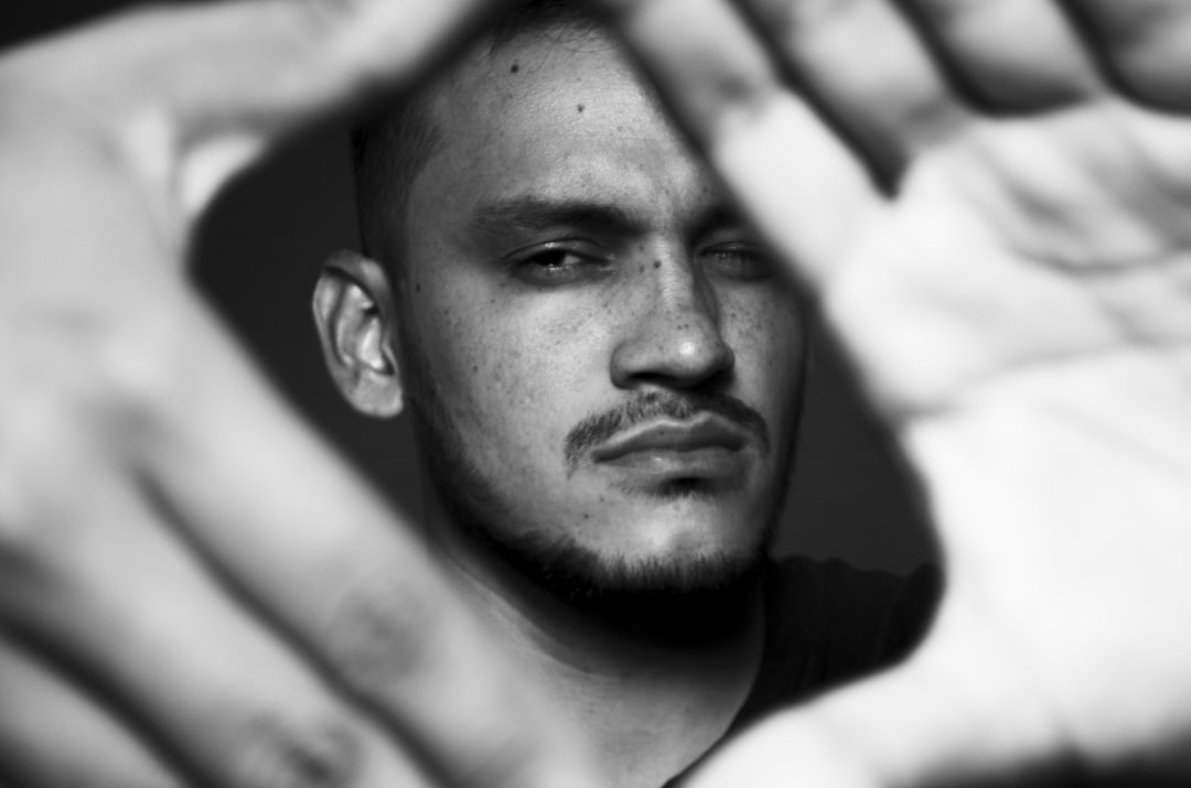 A black and white portrait of a Latino man with hands in the frame, shot on a Leica M6 using Portra 400 film stock in the style of the photographer. –ar 32:21