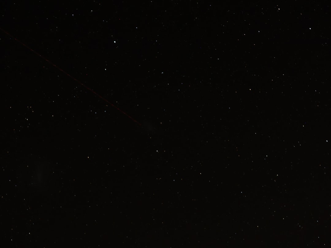 wide shot of black sky with few stars, one very thin and long red comet in the upper left corner –ar 4:3