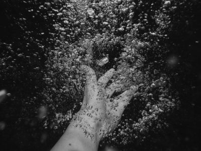 black and white photo of hand reaching out from under water, bubbles all around --ar 4:3