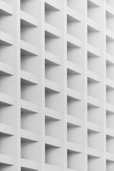 White architectural building facade, vertical grid pattern, minimalism, monochrome, high contrast, clean lines, architectural photography, geometric shapes, symmetrical composition, architectural detail, modern design, sleek and minimalist style. In the style of modern design. --ar 85:128