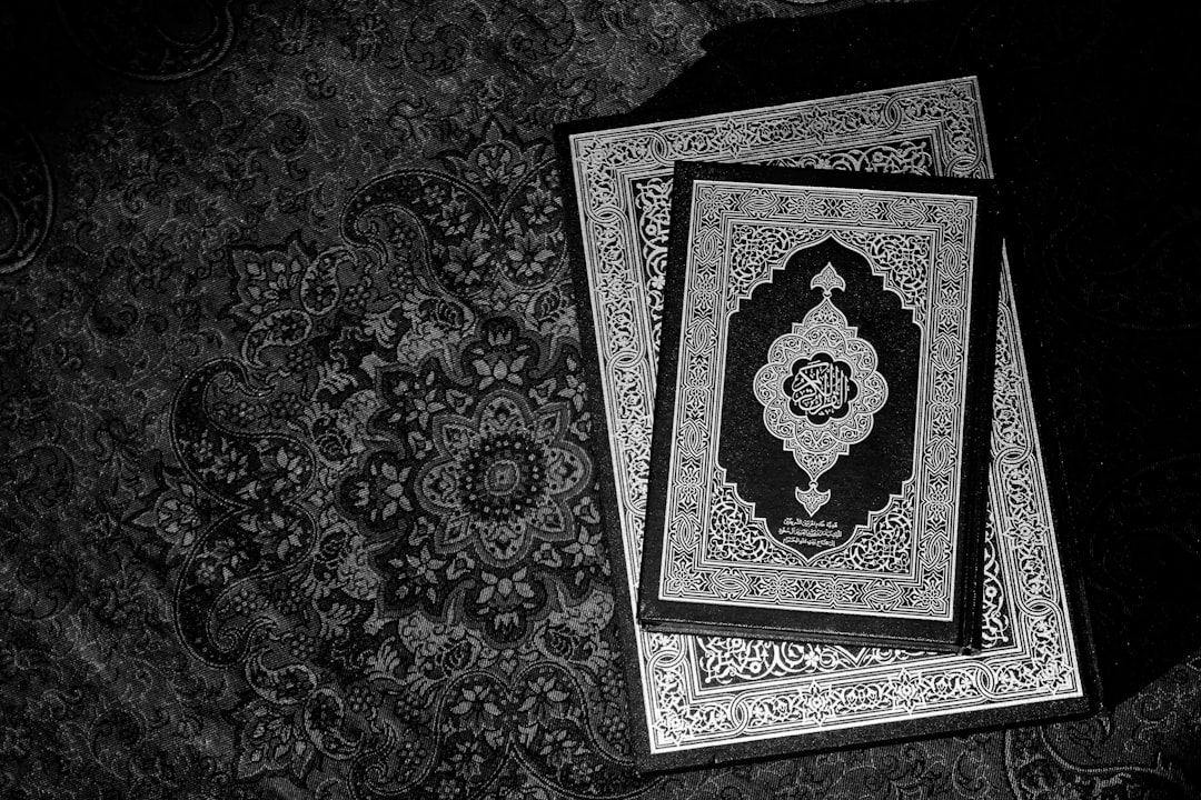 Black and white photograph of the two holy books, the Quran and Bible, on top of an Islamic pattern rug, with high resolution and intricate details, in the style of cinematic photography with cinematic lighting, dramatic shadows, and dynamic light reflections. –ar 128:85