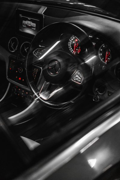 Black and white photography of the interior view from inside an mercedes amg, grainy film photo, high speed motion blur, modern car dashboard, steering wheel, radio and red lights --ar 85:128