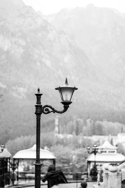 Black and white street lamp in the city of Kitzbuhel with mountains behind, shot on Leica M6 --ar 85:128