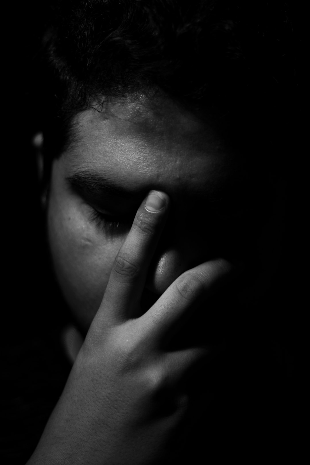 a hand covering the face of an indian boy, monochrome, strong contrast, dark background, sad mood, grainy texture, grain film, low light, chiaroscuro, silhouette lighting, professional photography, sharp focus, high resolution –ar 85:128