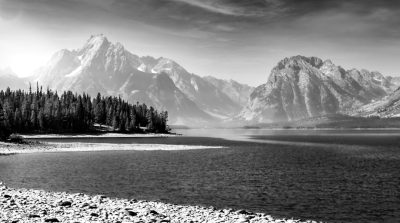 Black and white photo of the Grand Teton National Park with sharp mountains, trees on the shore, lake water, sky, high resolution, high detail, hyper realistic, award winning photography, in the style of HDR. --ar 128:71