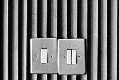 Black and white photograph of two light switches with the lights on, on a vertical slat wall. The photograph is in the style of a minimal edit of the original text, without any Chinese characters or repeated words. --ar 64:43