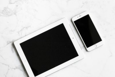 Photo of a tablet and phone on a white marble surface, in a flat lay style. Web banner with copy space on the right. --ar 128:85