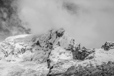 Black and white photography of the top of P:hidden mountain in the Andes introduces snow-covered peaks, with cloud cover. The majestic mountains create an epic atmosphere. Captured in the style of photographer Canon R6 Mark II. --ar 128:85