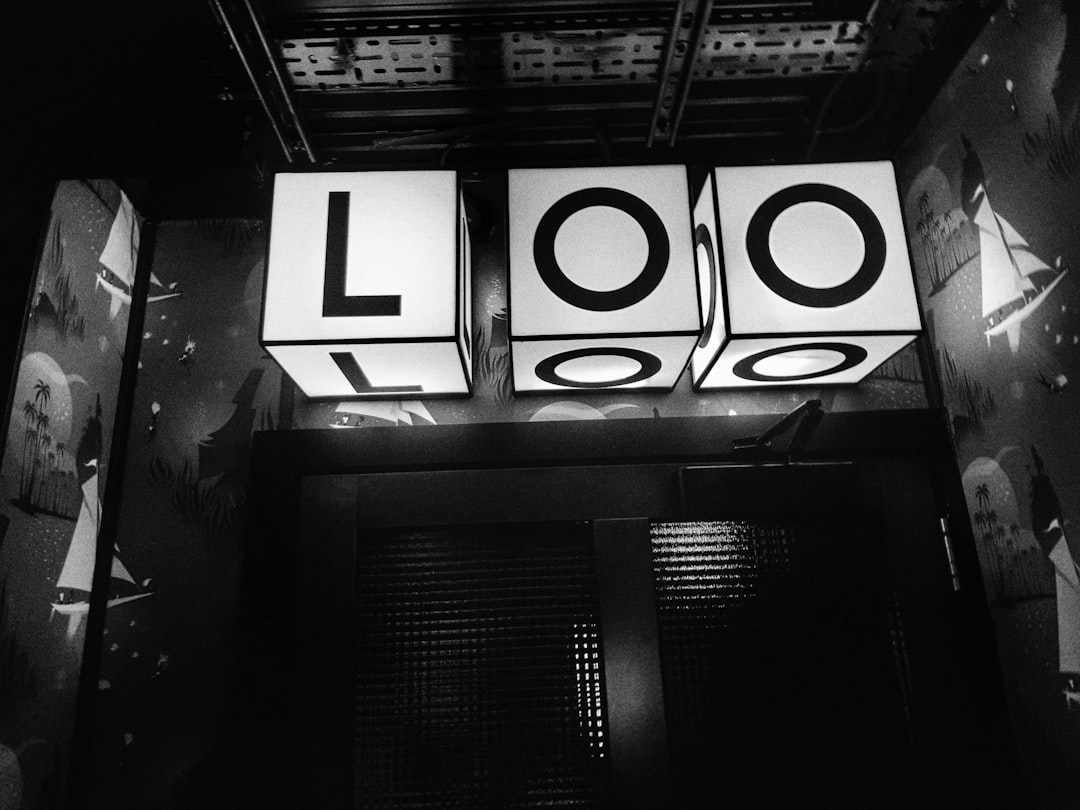 black and white photo of the word “LOO” in large letters on three glowing cubes, suspended above an immersive room with film posters, vintage movie posters, black background, cinematic lighting, atmospheric perspective, epic composition, volumetric light, hyper realistic, octane render, high resolution photography, photorealistic, shot by Hasselblad x2d camera, natural light, cinematic, editorial magazine –ar 4:3