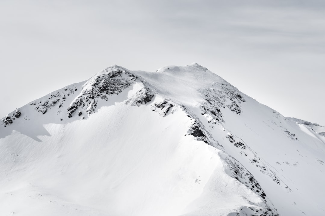 Snowy mountain peak, high contrast, stark white sky, sharp focus on the snowcovered summit, minimalist photography style, high resolution, Canon EOS R5 with an ultrawideangle lens, f/4 aperture for detailed texture capture, no people or human figures in sight. –ar 128:85