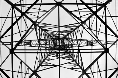 electricity provides nuanced photography in black and white. It features a close up of a power tower with a geometric and symmetrical composition. --ar 128:85