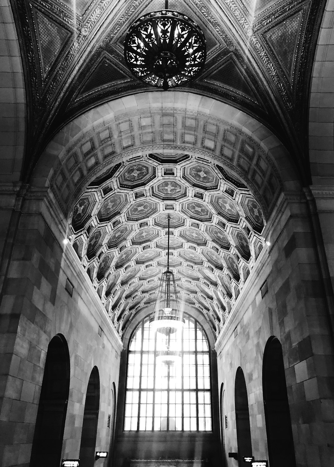 A black and white photo of the ceiling in an art deco building with ornate patterns, large windows, and arched doorways. The photo shows the ceiling in the style of an art deco architectural design. –ar 91:128