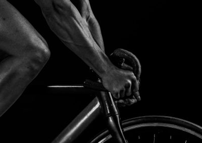 Close up of a male arm holding the handle bar of a bicycle, in black and white photography, a sports photograph, with high contrast, using studio lighting, against a black background. --ar 64:45