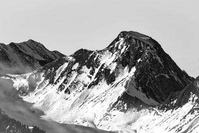 Black and white photo of snow-covered mountain peaks, with high contrast and sharp details. High resolution, high definition photography with stunning realism in the style of a professional photograph, taken in the style of a Sony Alpha A7R IV camera. --ar 128:85