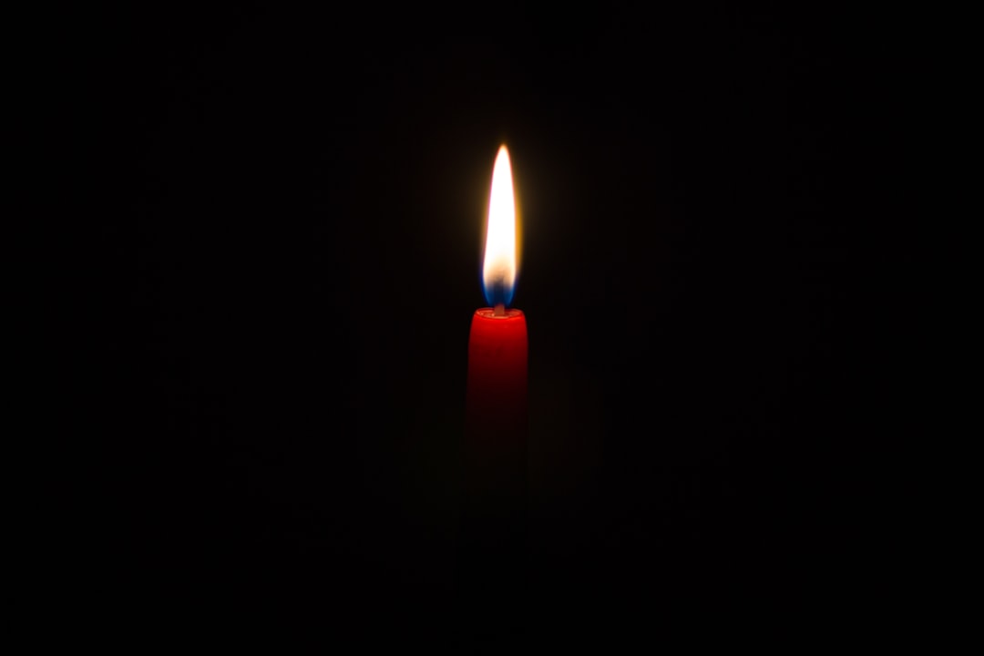 A single red candle burning in the darkness, symbolizing hope and reflection during Blackout night at Haslochitselboyen Heart fornighted heart with flame of love on black background. The simplicity captures the essence of introspection and unity amidst lightness. Photography, captured using a highresolution camera to highlight details against deep shadows, –ar 128:85