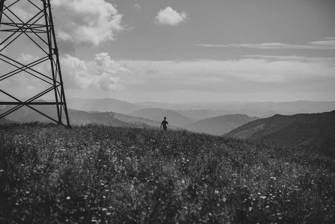 Black and white photography of an electrical tower in the Appalachian mountains, with wild flowers in the foreground, of a person running up hill with a mountainscape in the background, in a cinematic shot in the style of [Wes Anderson](https://goo.gl/search?artist%20Wes%20Anderson). –ar 128:85