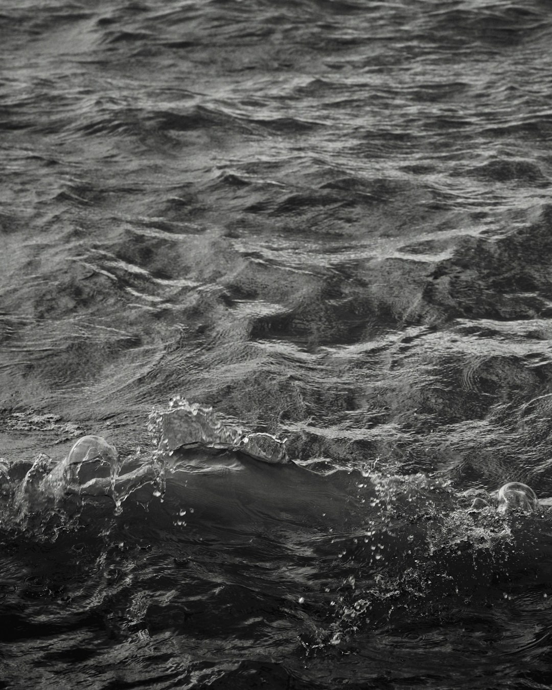 black and white photograph of the ocean, waves in the background, small bubbles visible on the surface, high contrast, dark tones, monochrome, high resolution photography, intricate details, detailed texture, natural lighting, professional color grading, depth of field, sharp focus, minimalistic style, in the style of [Misha Gordin](https://goo.gl/search?artist%20Misha%20Gordin). –ar 51:64