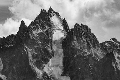 Black and white photo of the sharp peaks of Chombies de la Throne in Aatiachuan, France. The mountain is covered with snow and has many cliffs that create an impressive scene. In the background you can see some clouds. Shot on Nikon D850 camera using Nikon AFS NIKKOR 24-70mm f/2.6E ED VR lens. High resolution, high details, in the style of hyperrealism. --ar 128:85