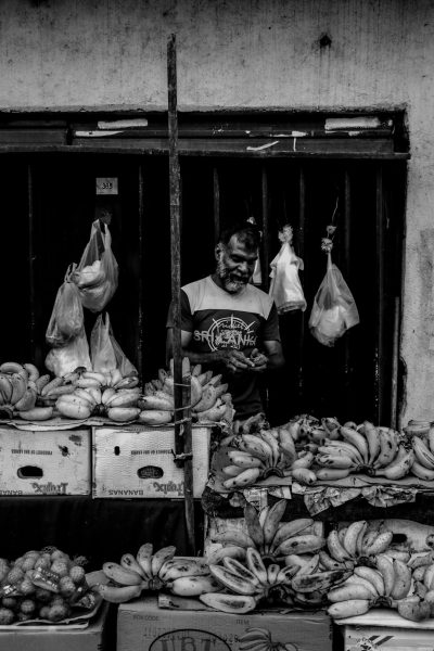 A greengrocer selling bananas in the streets of Panama, in the style of black and white photography, minimally editing the original text. --ar 85:128