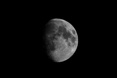 The moon is seen against the black sky, with its half lit surface in a grayscale style. Shot on Canon EOS R5 using a macro lens. --ar 128:85