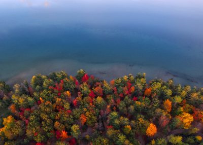 Aerial view of a colorful autumn forest on the shore of Lake Michigan, captured in the style of DJI Mavic Pro with a high resolution camera. --ar 128:91