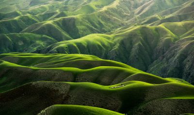 The undulating green hills of the Valley, in the style of National Geographic magazine, top view, hyper realistic photography, award winning photography, natural lighting, sunny day, cinematic light --ar 32:19