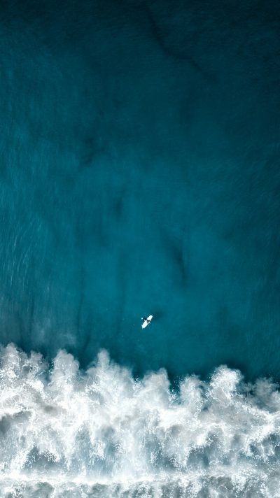 Aerial view of a surfer in the ocean, minimalistic wallpaper with a minimalist style and a blue and white color palette. High resolution, high quality, high detail image with a hyper realistic and super detailed look resembling photo realism and high definition with high contrast. The natural lighting and natural colors give it a cinematic and photographic quality, captured in the style of sony alpha m5 mark iii. --ar 71:128