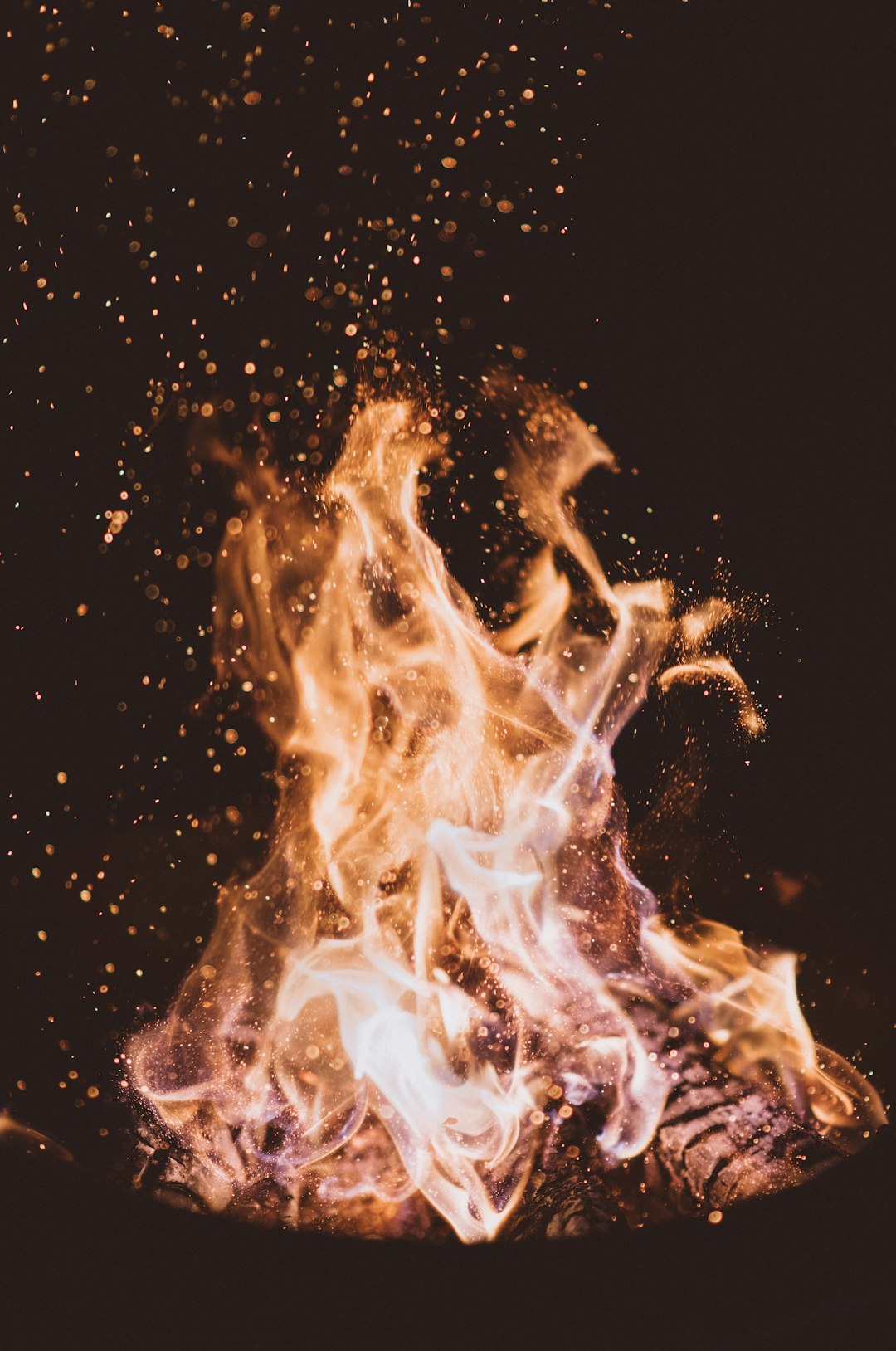 A photo of the flames in front, the fire is burning on top and below, the sparks flying out from under it are shining like gold dust. The background color has black as an element, which adds depth to your visual experience. It’s a real photograph taken with professional cameras. –ar 21:32