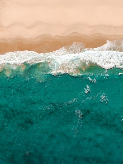 Aerial view of turquoise ocean waves and sand, warm tones, photo realistic, in the style of canon eos r5. --ar 3:4