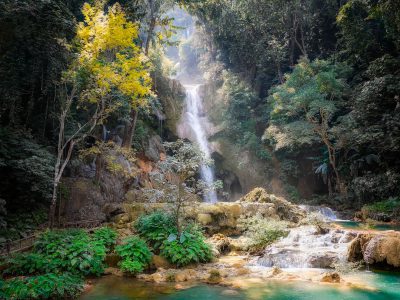 A beautiful waterfall in the lush forest of Lao. A high quality photo in the national geographic style, of a waterfall in Laos, with vibrant colors, jungle, turquoise water, green trees, yellow leaves, rock cliff, natural lighting, sun rays, water spray, natural beauty, peaceful atmosphere, relaxing. --ar 4:3