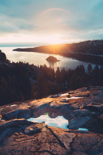 professional photo of Lake Tahoe, sunset, snow on rocks, Emerald Bay, camera is looking down at the water from top to bottom, golden hour sun in sky, small island with trees visible across the lake. --ar 85:128